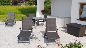 Eine Terrasse im Freien mit Korbmöbeln, einem Tisch und einem kleinen runden Beistelltisch.