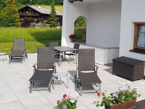 Eine Terrasse im Freien mit Korbmöbeln, einem Tisch und einem kleinen runden Beistelltisch.