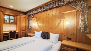 Ein Zimmer mit Holzboden, einem Bett, einem Schreibtisch und einem Stuhl.