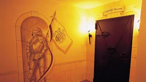 Een hal met een deur waarop 'Schloß-Sauna' staat en een aan de muur bevestigd embleem.