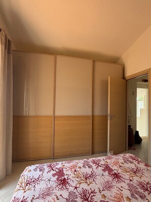 A bedroom with a bed, a wardrobe, and a door leading to another room. - Villa Faro Sea (San vito lo capo)