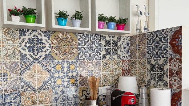 A kitchen with a gas stove, a coffee maker, and various potted plants on shelves. - Villa Faro Sea (San vito lo capo)