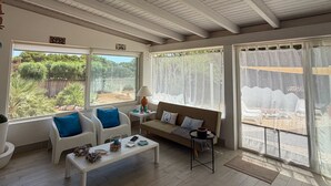 A spacious living area with a high ceiling, a sofa, two armchairs, a coffee table, and a view of the outdoors through large windows. - Villa Faro Sea (San vito lo capo)