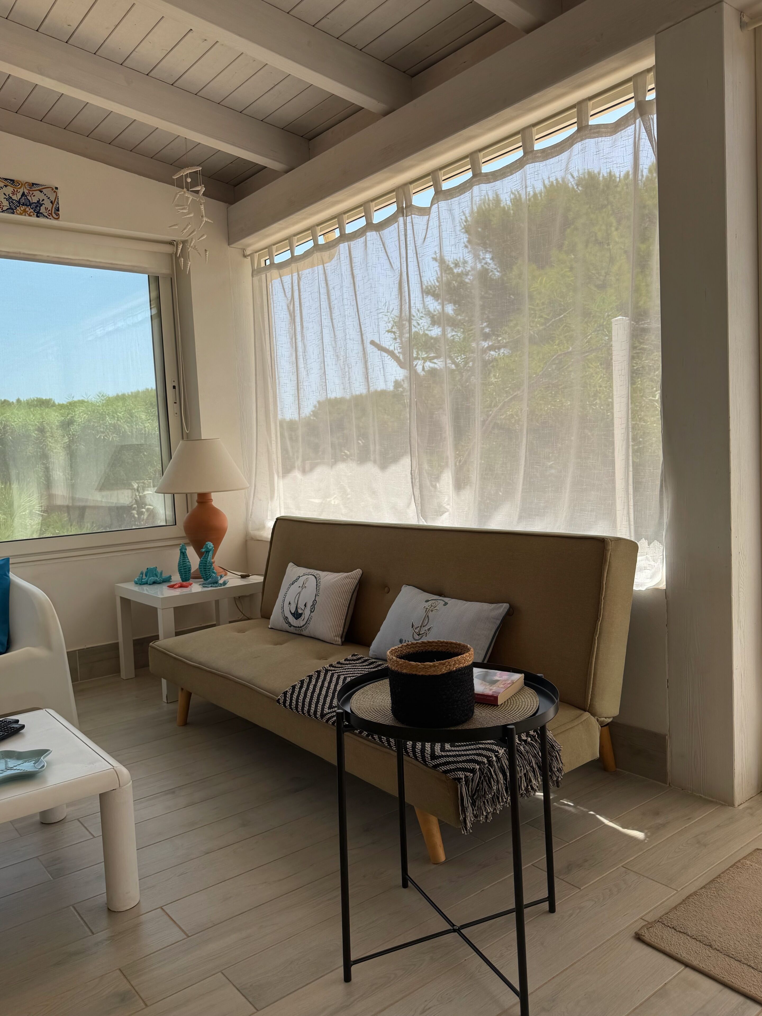 A cozy room with a sofa, a small table, and a window with sheer curtains.