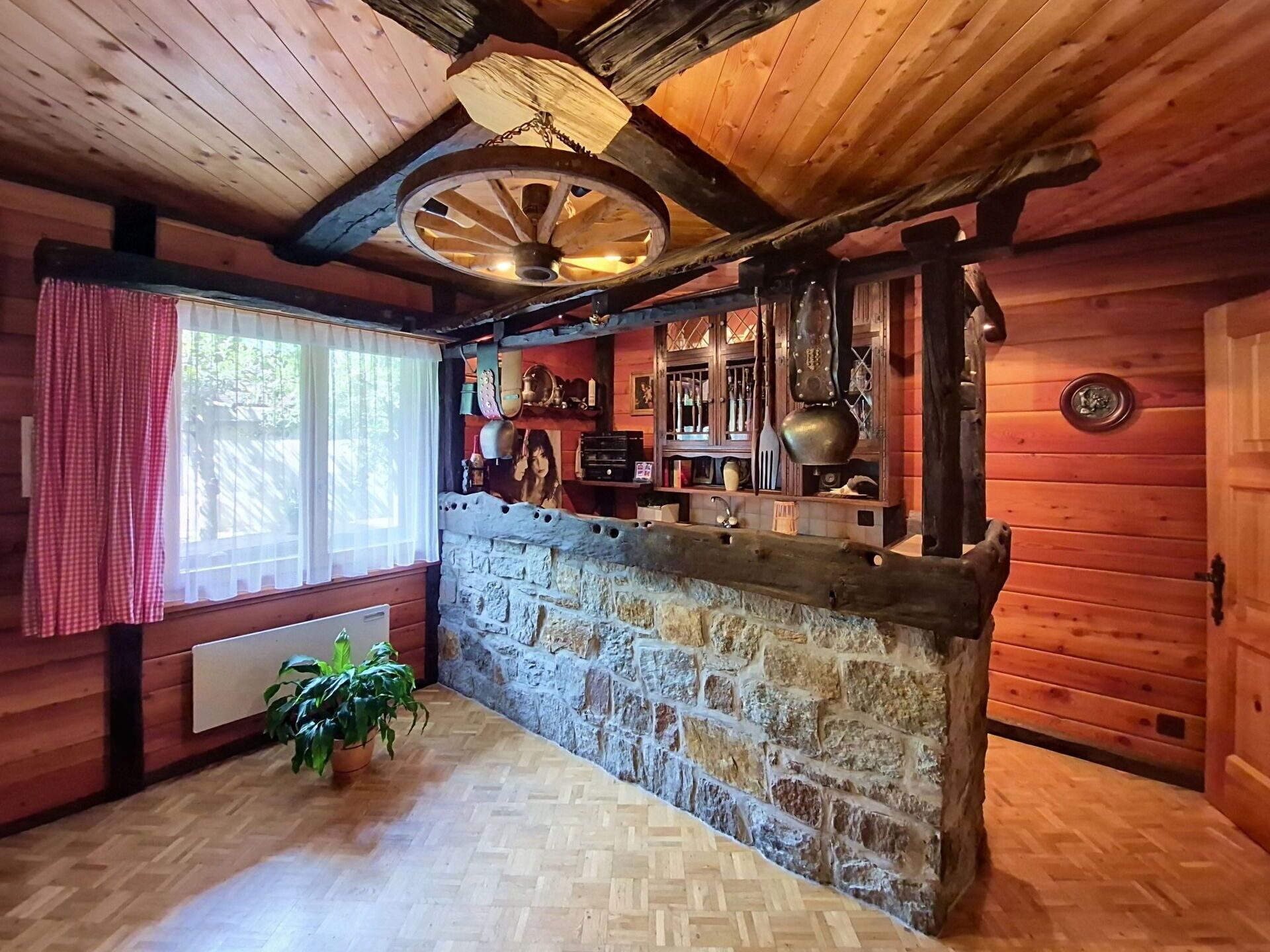 A rustic interior with wooden walls, a stone counter, and a ceiling fan.