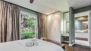 Ein Schlafzimmer mit Bett, einer Bank, einem Spiegel und Blick ins Grüne.