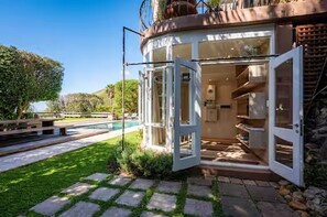 A modern house with a glass door leading to a well-lit interior, a stone pathway, and a pool in the background. - Spacious spectacular 9-bedroom Fresnaye Villa (Cape Town)