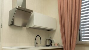 Una cocina moderna con lavavajillas integrado, campana extractora de acero inoxidable y ventana con persianas.