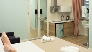 Una habitación de hotel moderna con cama, escritorio, kitchenette y baño.