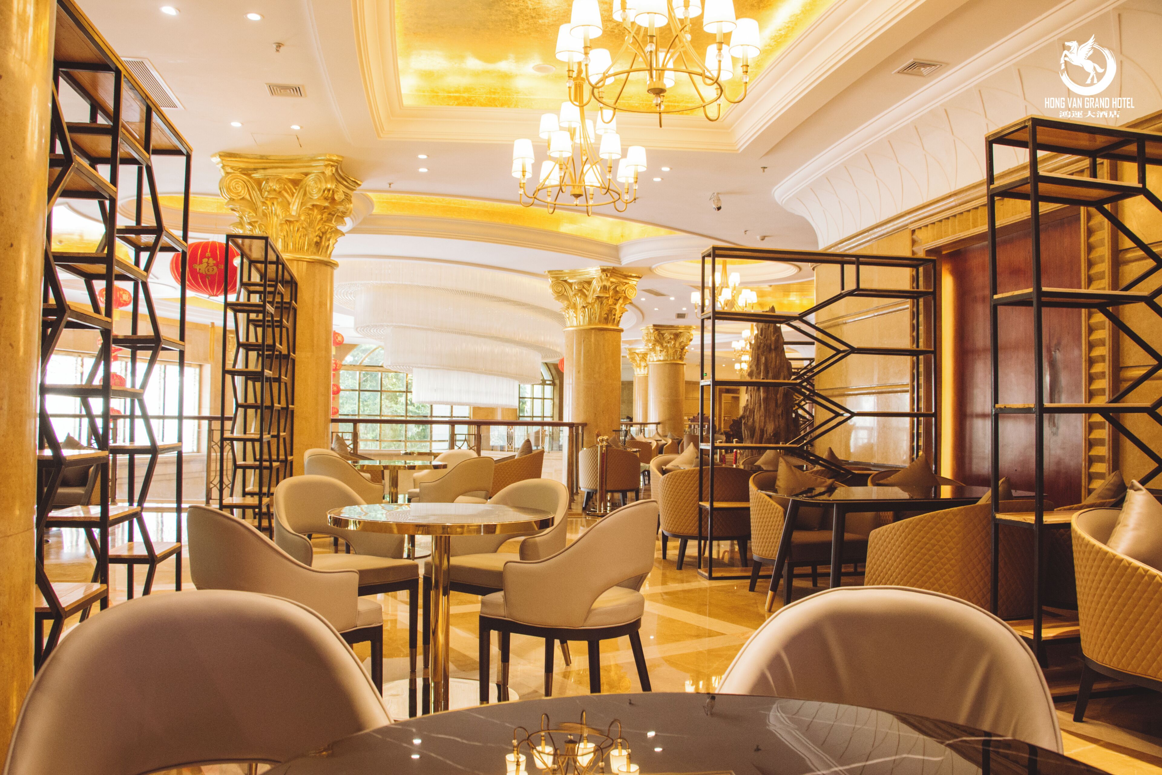 Eine Hotelhalle mit einer Kristallleuchter, einer Sitzecke und Bücherregalen.