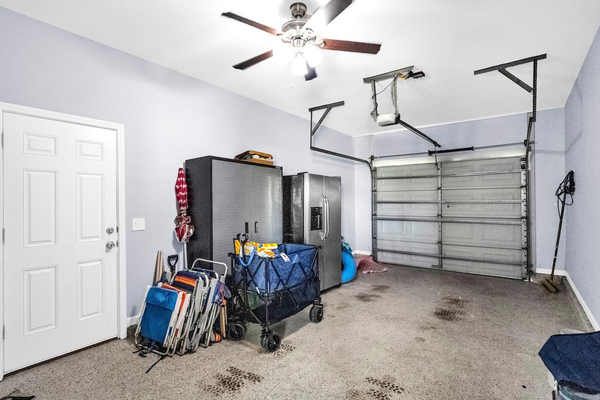A garage with a ceiling fan, a metal garage door, and a cart with luggage.