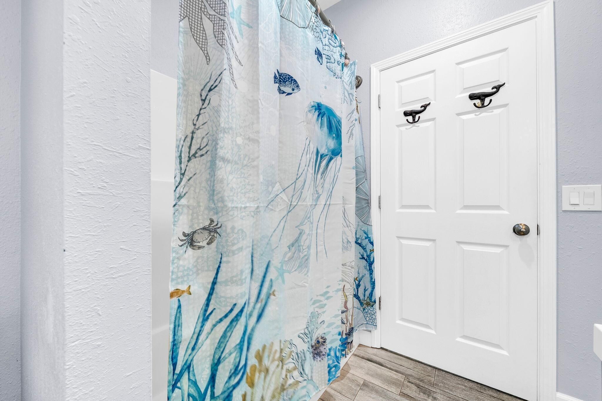 Un couloir avec une porte blanche, un mur blanc à texture et un rideau à motifs bleus et blancs.