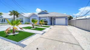 A residential property with a driveway, a garage, and a well-maintained lawn with palm trees. - Shaker of Salt (Panama City Beach)
