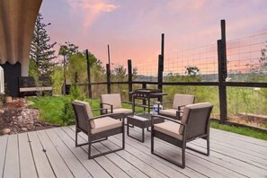 Eine Terrasse im Freien mit Tisch, Stühlen, einem Grill und Blick auf die Landschaft.