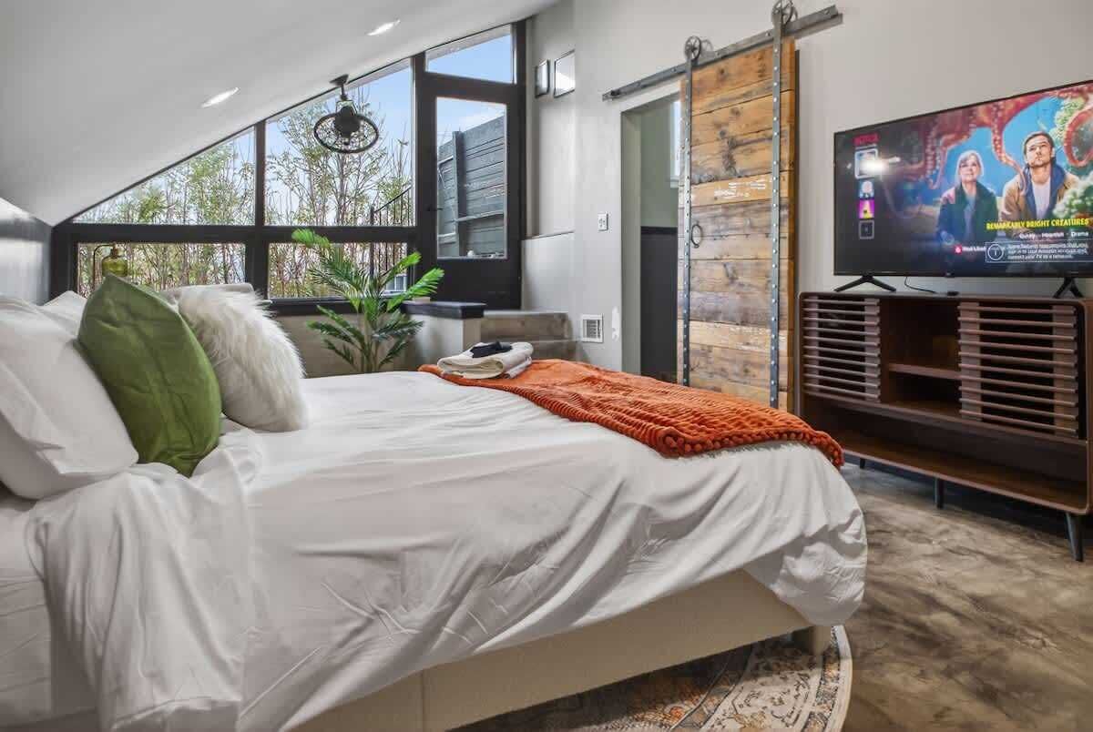 A bedroom with a bed, a TV, and a large window.
