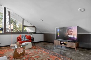 A modern living room with a large flat-screen TV, a red sofa, a glass coffee table, and a patterned rug. - Mid-Century Mountain View Getaway for 4 (Billings)