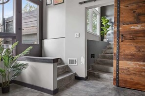 A staircase leading to a landing with a wooden door, a potted plant, and a window. - Mid-Century Mountain View Getaway for 4 (Billings)