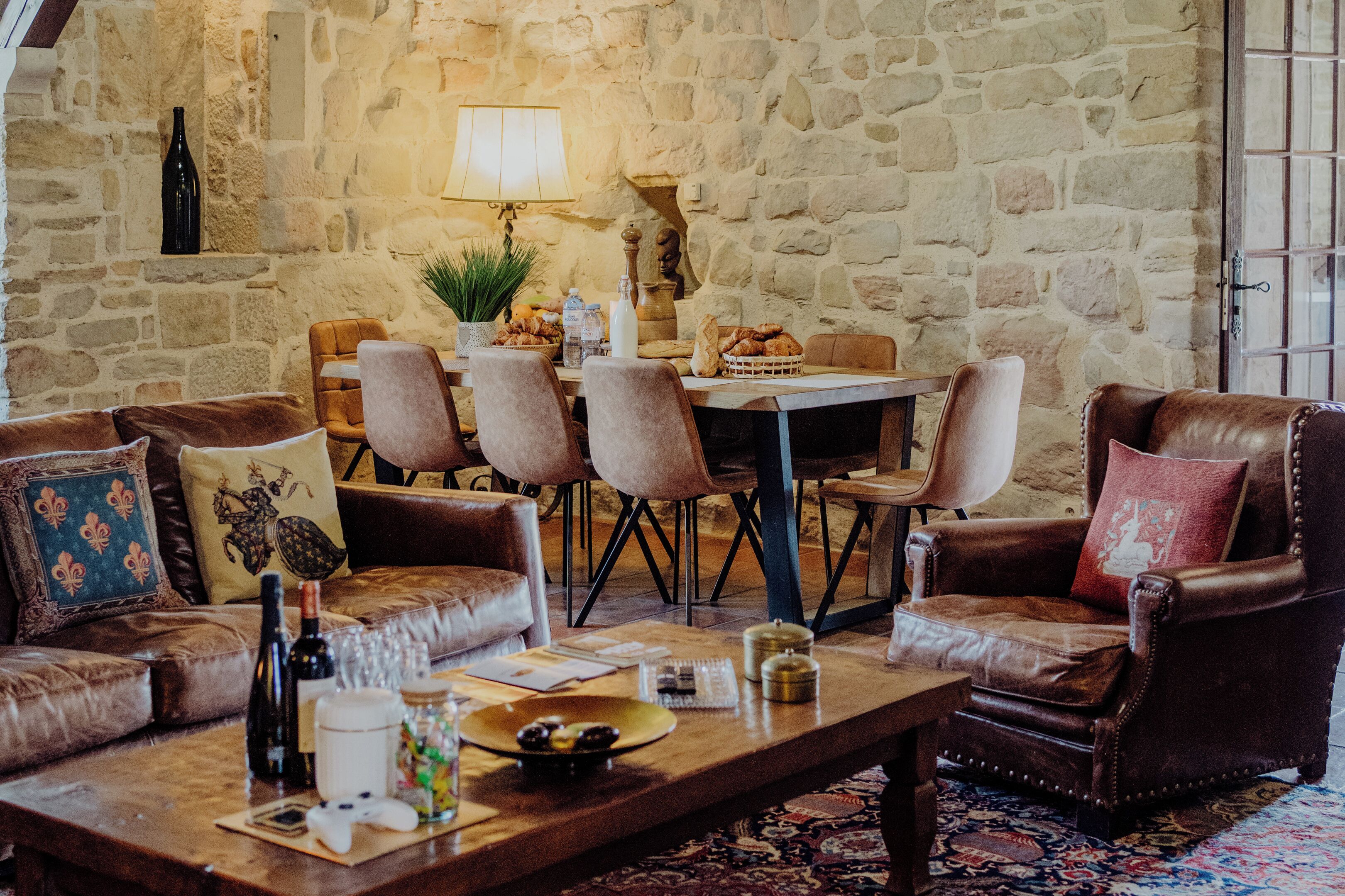 A cozy living room with leather sofas, a wooden coffee table, and a stone wall.