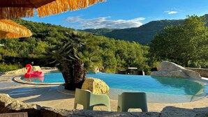 Uma piscina com um flutuador de flamingo vermelho, uma palmeira e montanhas ao fundo.