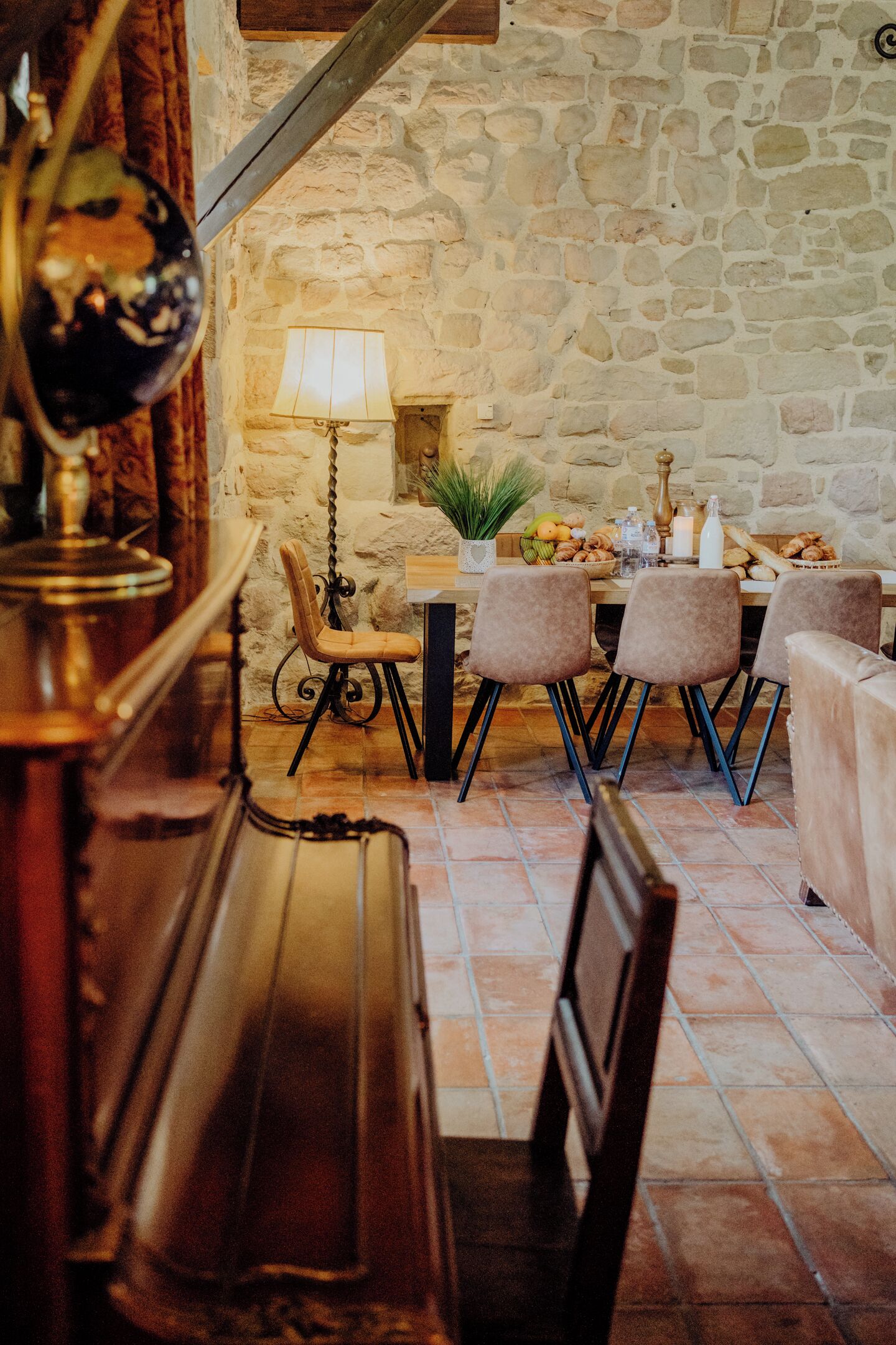 Un coin repas rustique avec des murs en pierre, une table en bois et plusieurs chaises rembourrées.