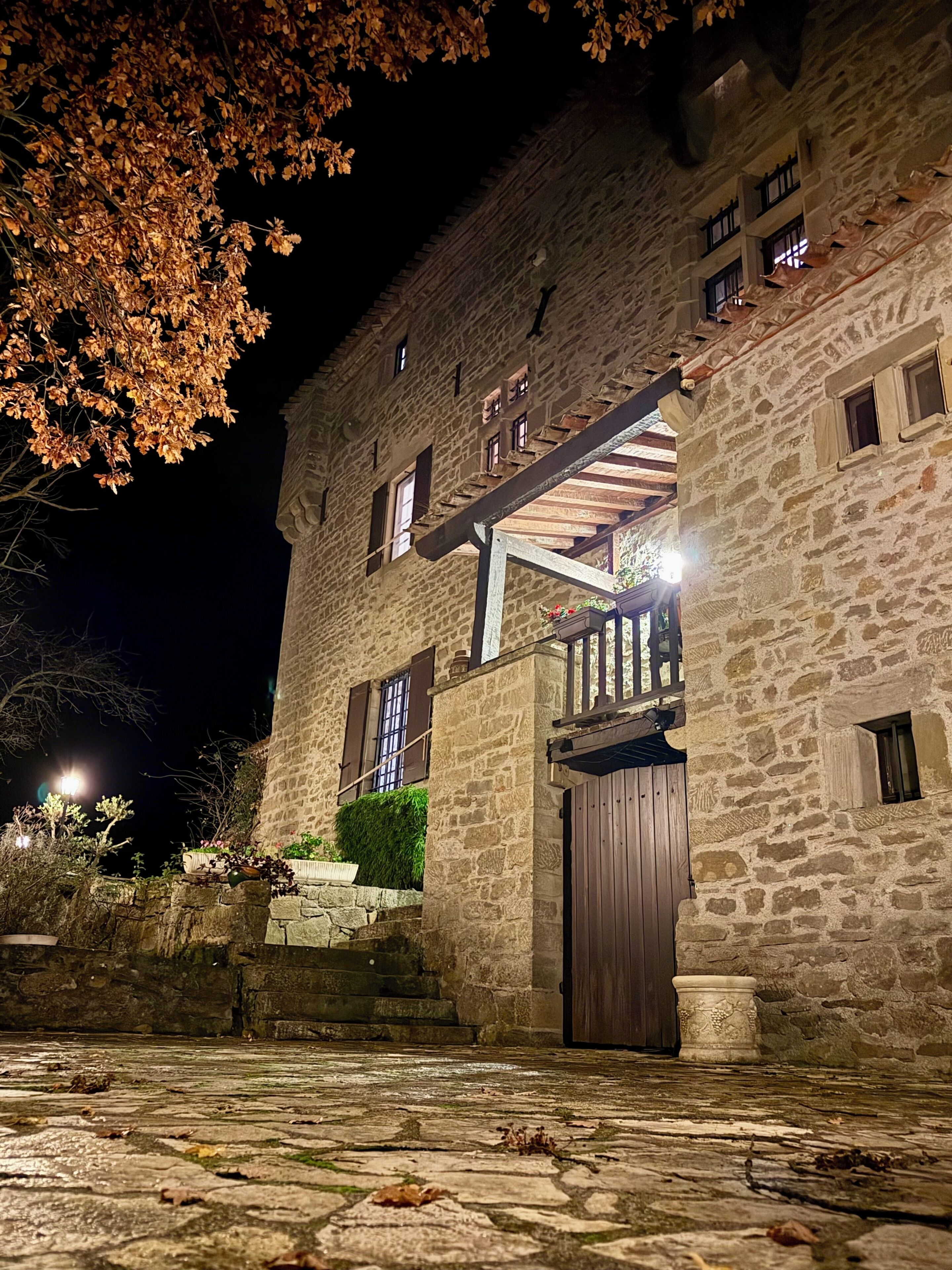 Un bâtiment en pierre avec une porte en bois, un escalier et un balcon.