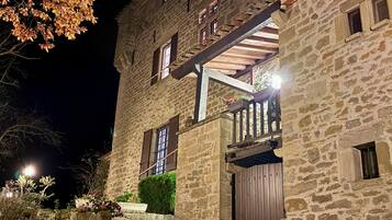 Un bâtiment en pierre avec une porte en bois, un escalier et un balcon.
