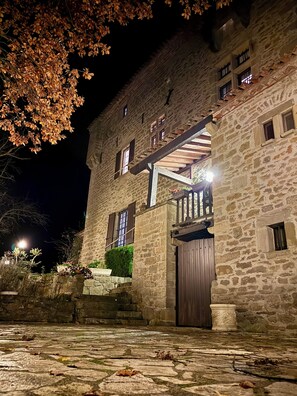 A stone building with a wooden door, a staircase, and a balcony.