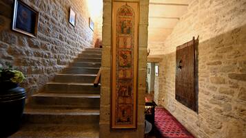 Un escalier en pierre menant à un niveau supérieur, une porte en bois ornée d’un panneau décoratif et un tapis à motifs.