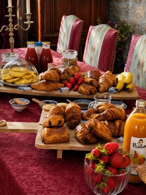 A breakfast buffet with pastries, fruits, and condiments.