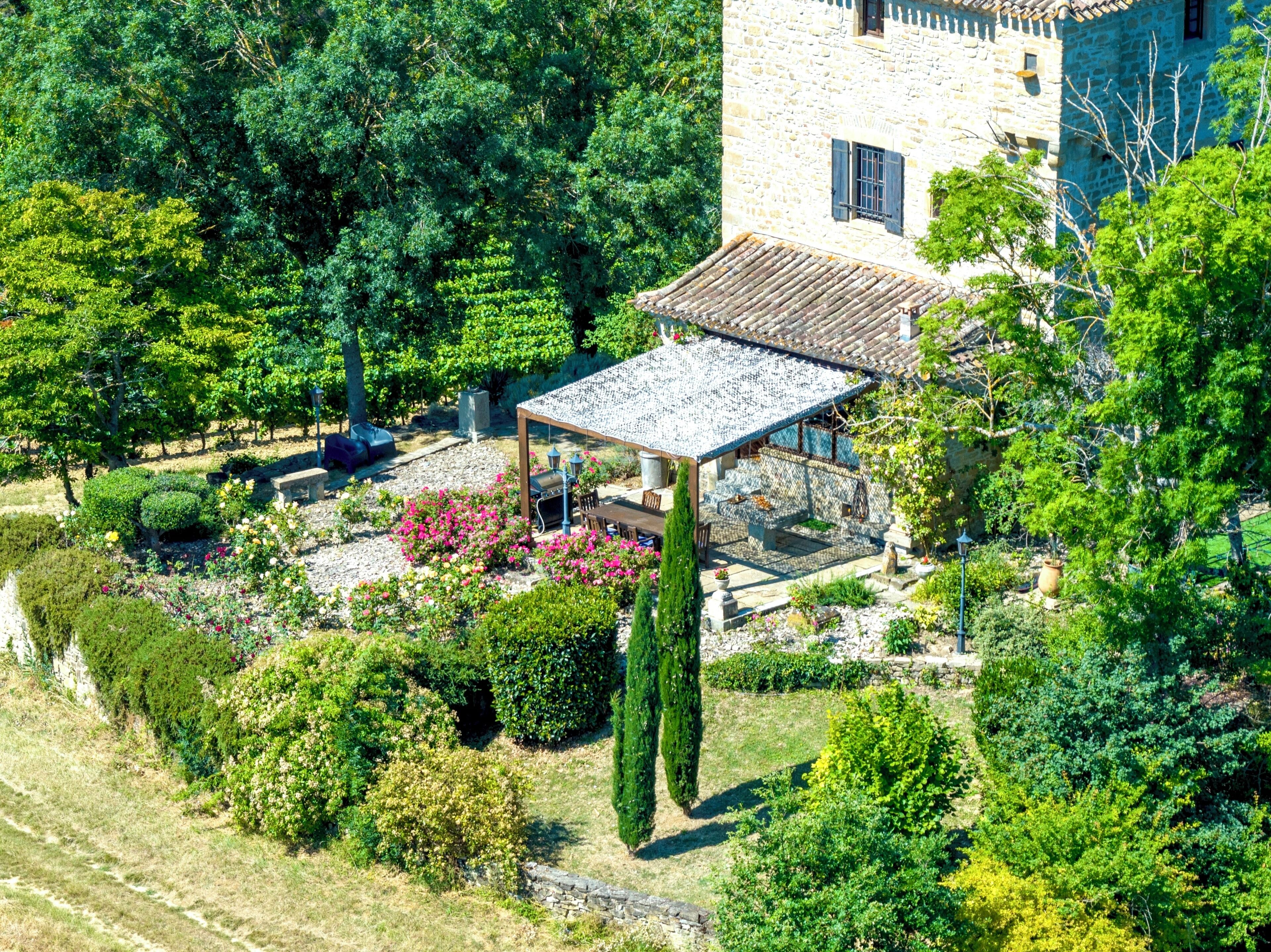 A stone building with a covered patio and lush garden.