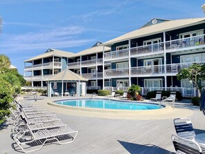 Ein mehrstöckiges Hotel mit Poolbereich, inklusive Liegestühlen und einem Pavillon.