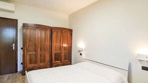Une chambre à coucher avec un lit, une armoire en bois et un luminaire fixé au mur.