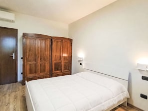 Ein Schlafzimmer mit einem Bett, einem Holzschrank und einer Wandleuchte.