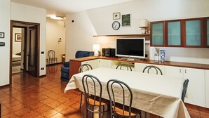 Un espace de vie compact comprenant un coin repas, une kitchenette et un téléviseur.