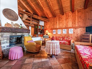 Ein gemütliches Zimmer mit Kamin, Holzwänden, einer Couch, einem Tisch und einem Bett.
