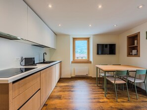 Cozinha compacta com área de refeições, janela com vista e TV de tela plana na parede.