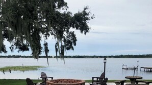Un vialetto lastricato conduce a un'area con un braciere, poltrone Adirondack e un tavolo, con vista su un lago.