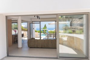 Ein modernes Interieur mit einer Schiebetür zu einem Poolbereich, einer Sitzecke mit einer Couch und einem Essbereich.