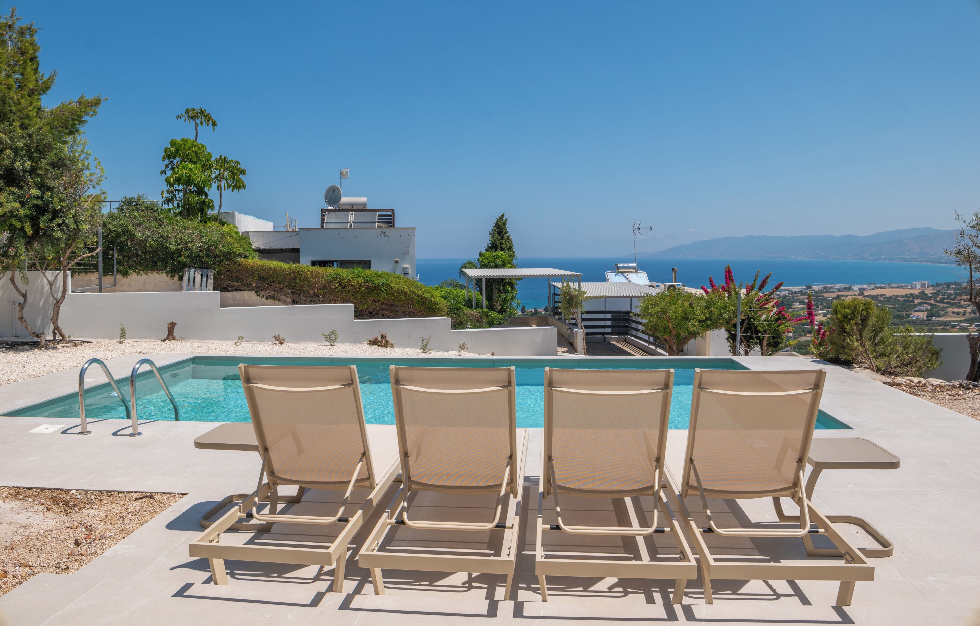 A poolside area with lounge chairs and a view of the sea.