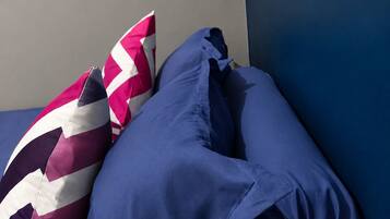 Una cama con dos almohadas, una con estampado en zigzag y la otra de color azul liso.