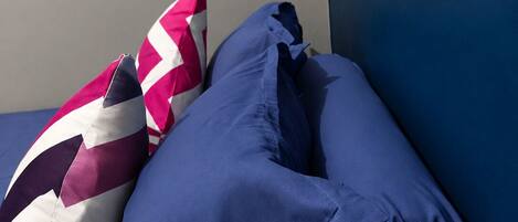A bed with two pillows, one with a zigzag pattern and the other solid blue.