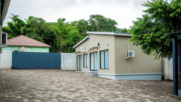 A building with a tiled courtyard, a gated entrance, and a satellite dish.
