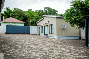 Un bâtiment doté d’un toit plat, d’une cour pavée et d’une entrée fermée par un portail.