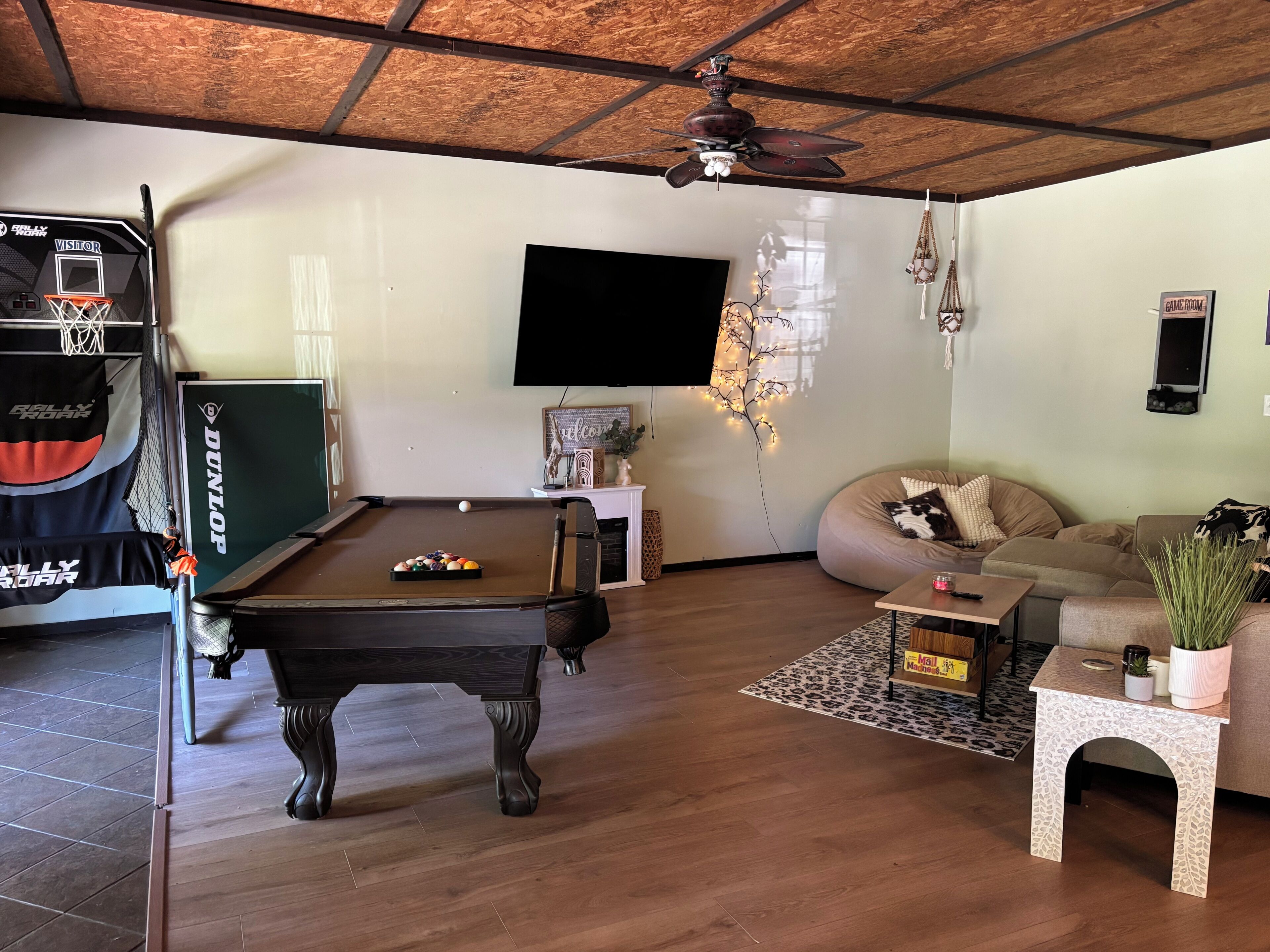 A pool table, a sofa, a television, and a ceiling fan in a living room.