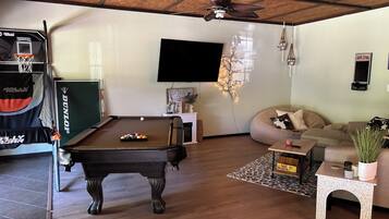 A pool table, a sofa, a television, and a ceiling fan in a living room.