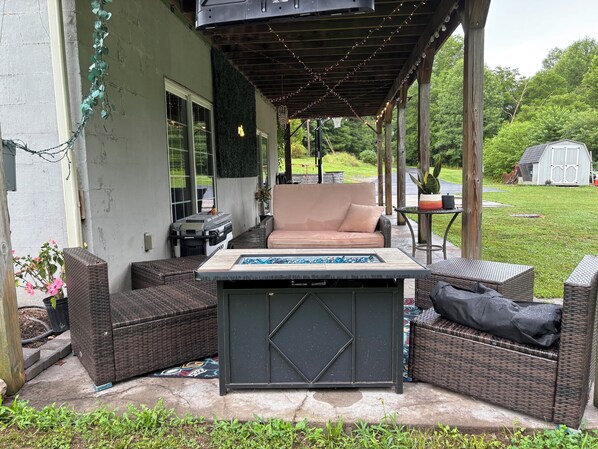 An outdoor patio with wicker furniture, a table, and a grill.