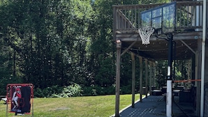 En basketplan med en basketkorg, ett överbyggt sittområde och en skylt med en basebollspelare.