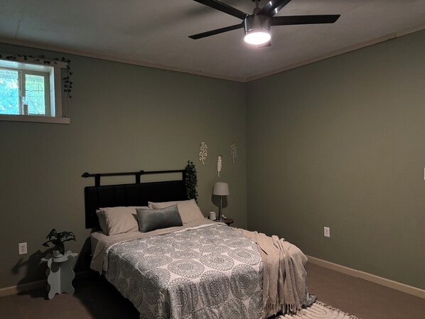 A bedroom with a bed, a ceiling fan, a window, and wall decorations.