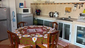Keittiössä on ruokapöytä, tuoleja, mikroaaltouuni, vedenkeitin ja pesuallas.
