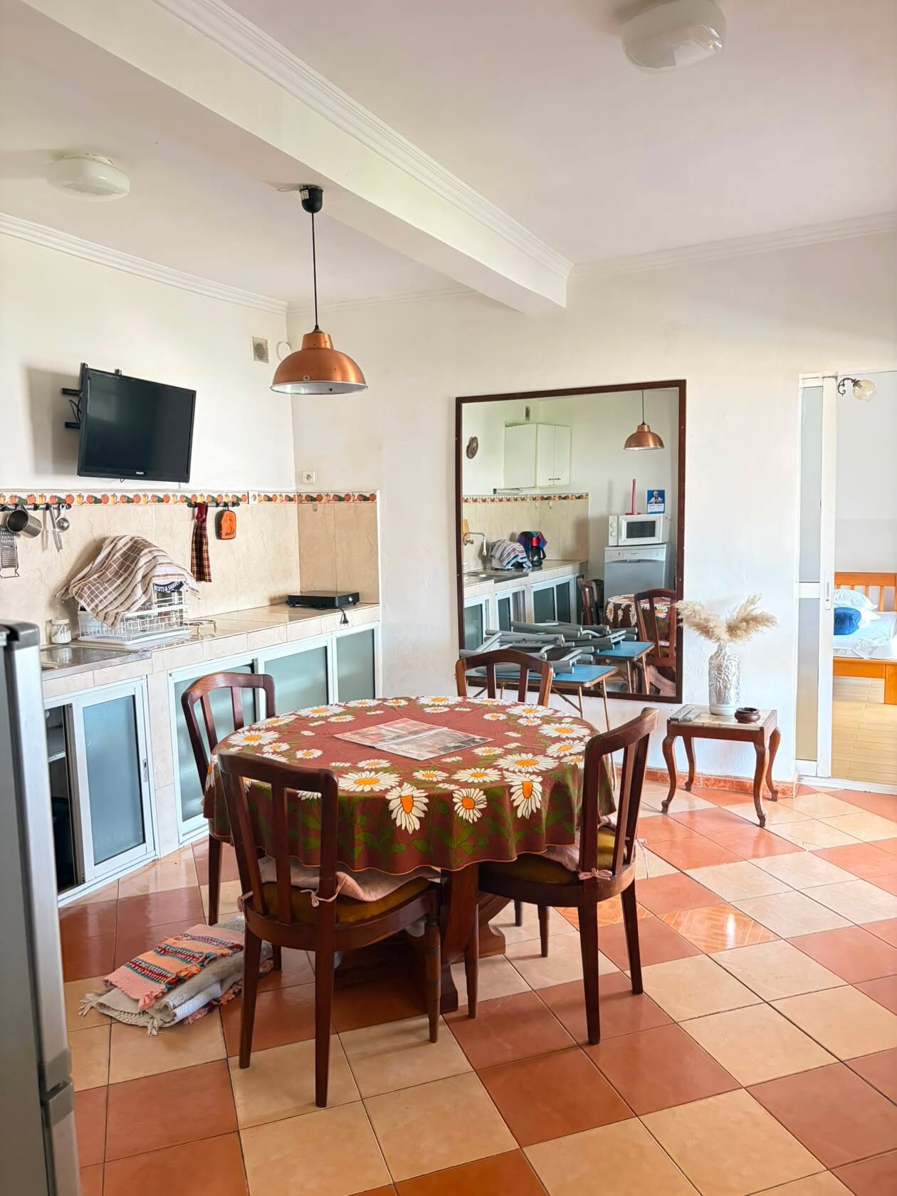A dining area with a round table, chairs, and a kitchen in the background.